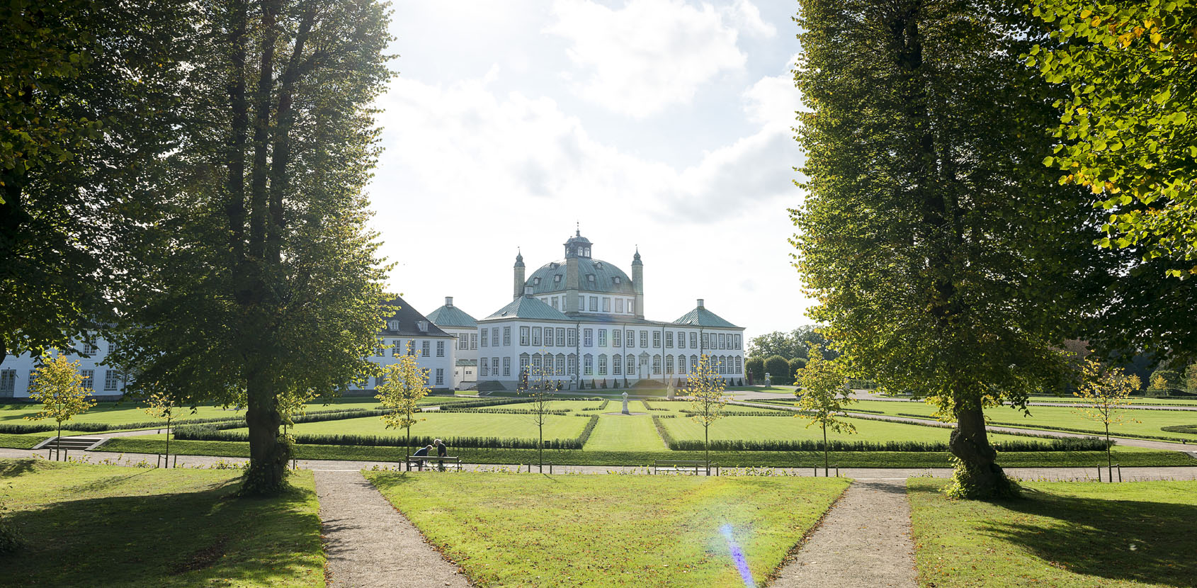 Omvisninger i Fredensborg Slotshave, Danmarks største historiske barokanlæg søndage i maj kl. 11.00 og 14.00 Fredensborg Slot med træer i forgrunden. Foto: Thomas Rahbek